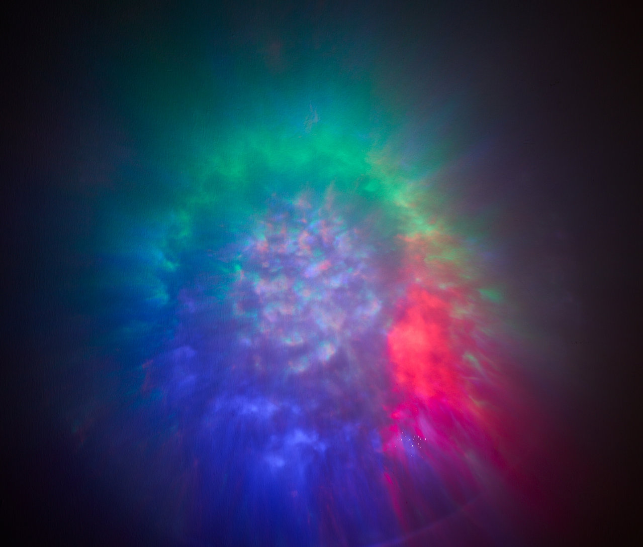 Abstraktné pozadie s rozmazanými svetlami v odtieňoch modrej, zelenej a červenej.