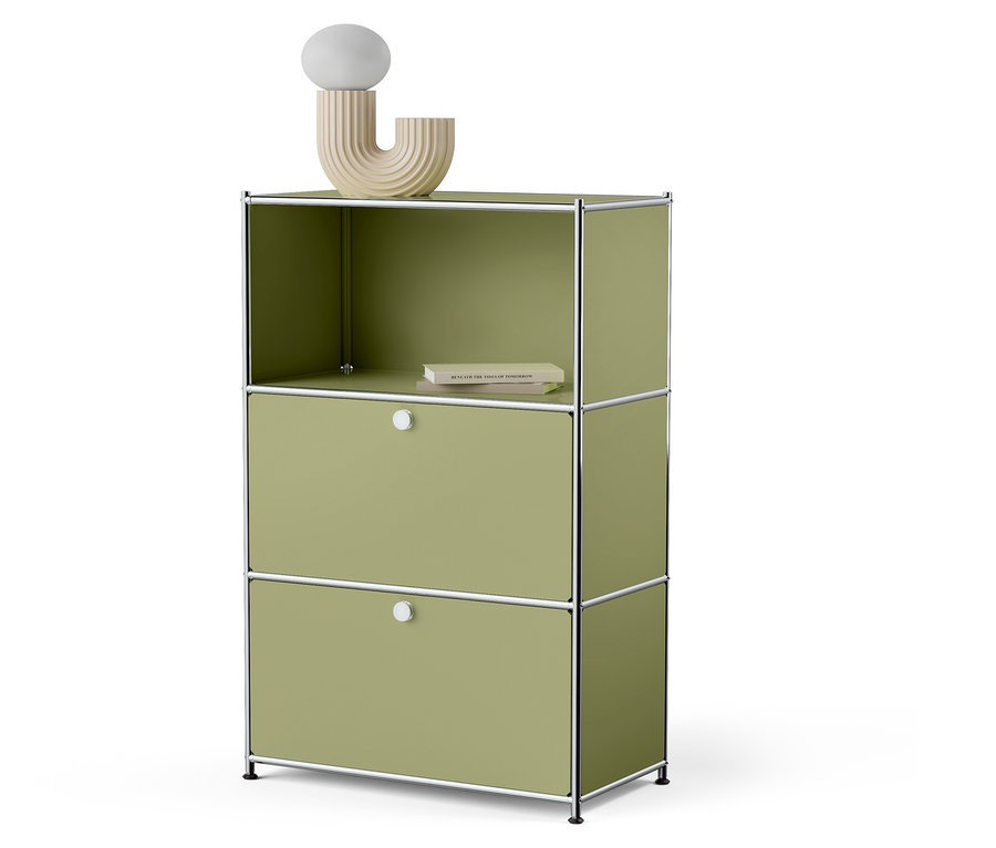 Zelená skrinka s dvomi zásuvkami a otvorenou hornou policou, na ktorej leží kniha a stojí dekoratívna lampa.