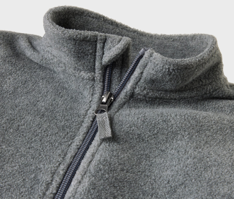 Detail sivého flaušového overalu pre deti s otvoreným zipsom.