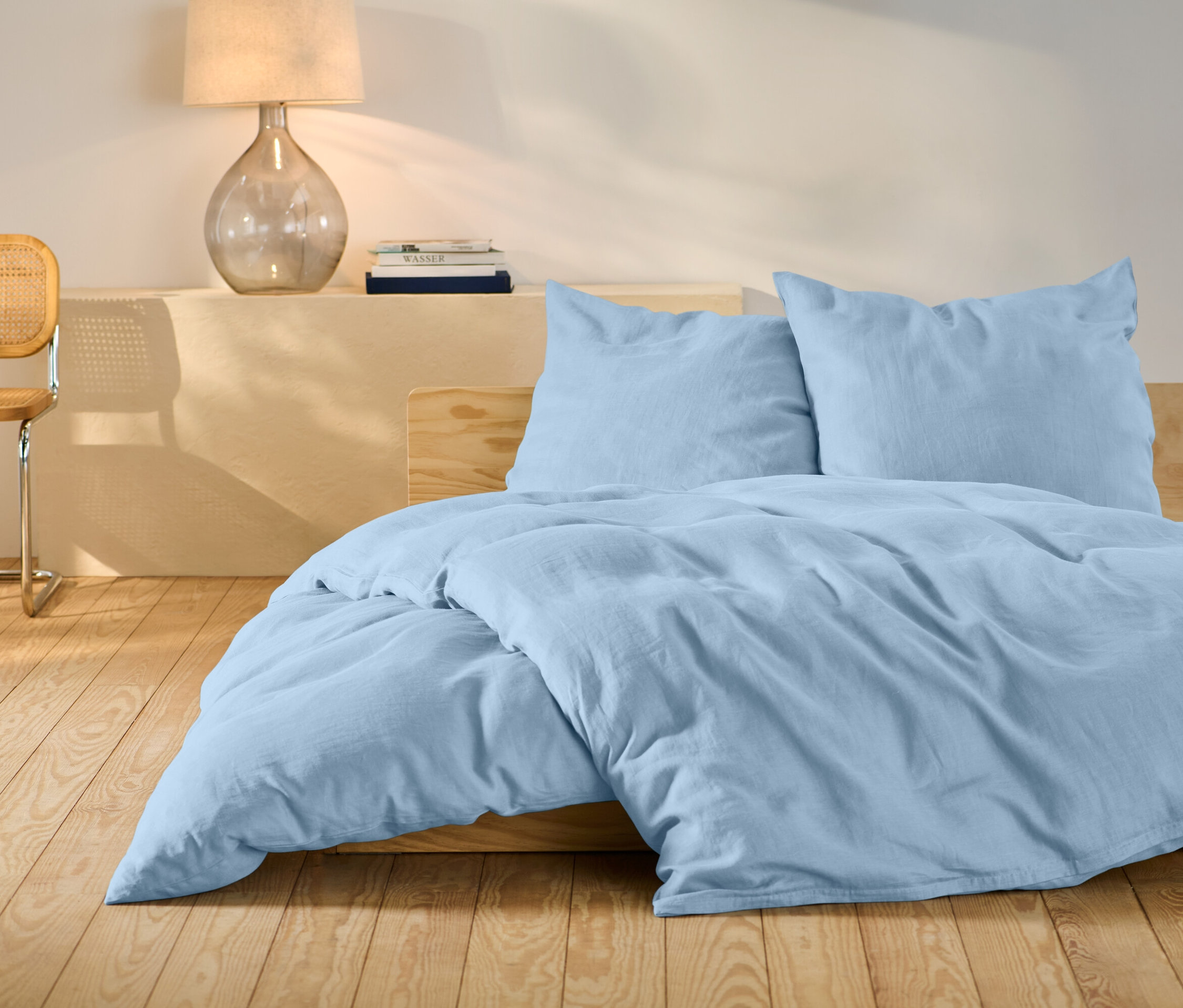 Svetlomodré ľanové obliečky štandardnej veľkosti na posteli.