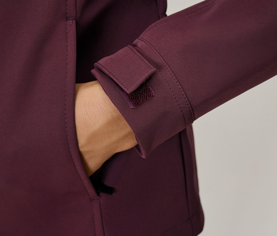 Ruka vo vrecku bordovej bundy, detaily ako manžeta na suchý zips.