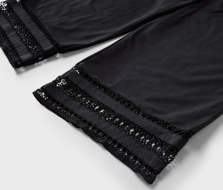 Detail čiernych nohavíc culottes s výšivkou na leme.