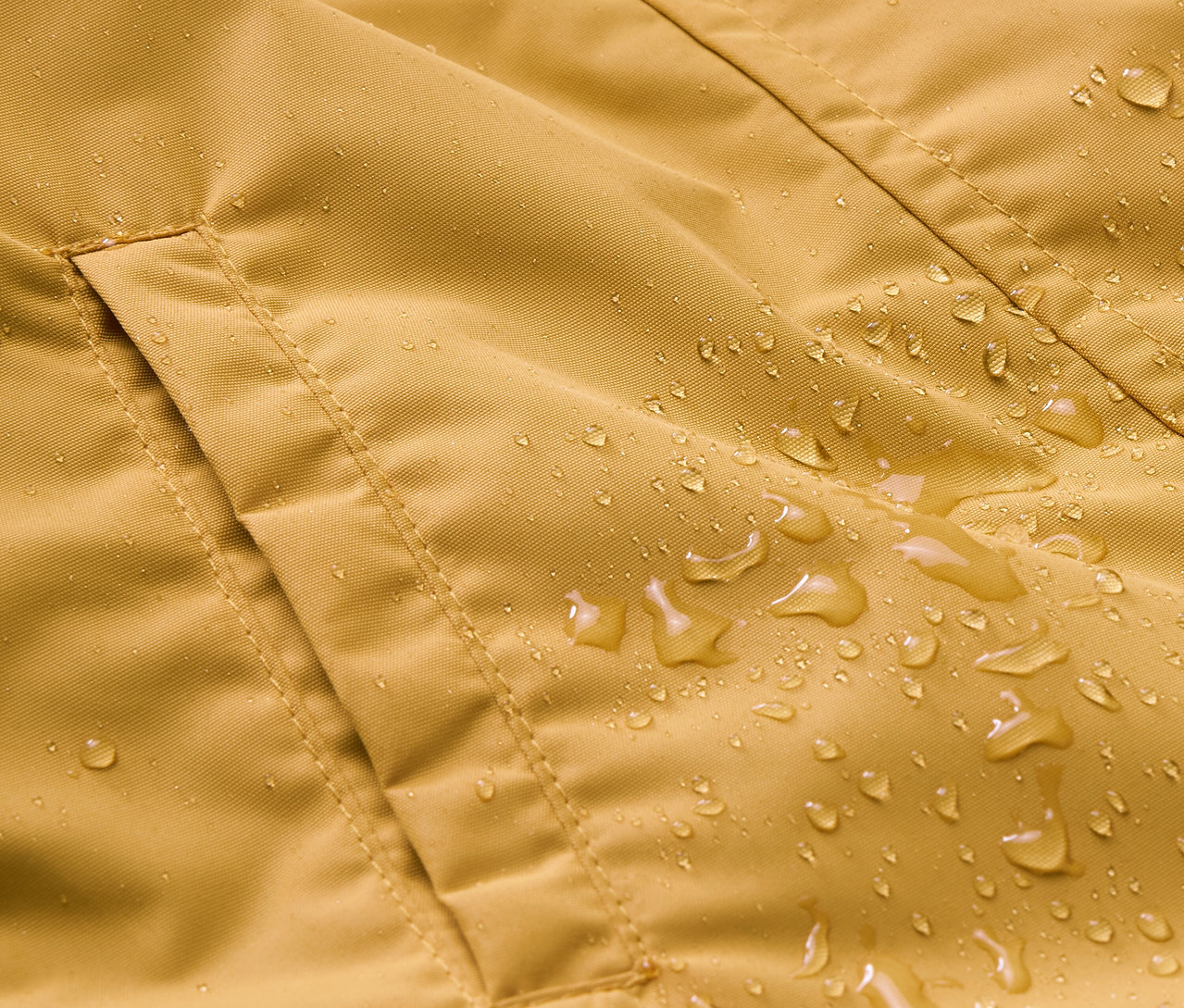 Detail detskej kombinézy do dažďa s vreckom a kvapkami vody.