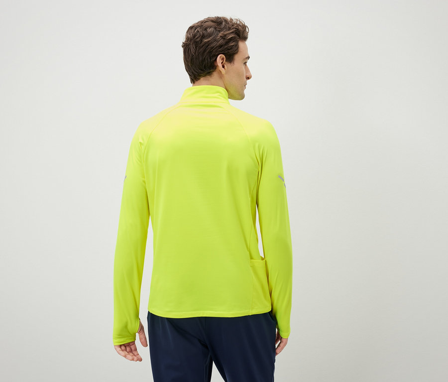 Muž chrbtom k fotoaparátu má na sebe neónovo žltý športový top s dlhým rukávom.