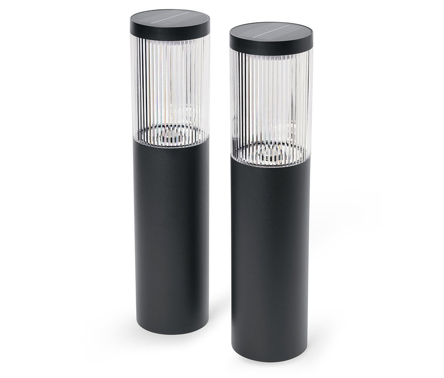 Dve čierne solárne lampy stoja na bielom pozadí.