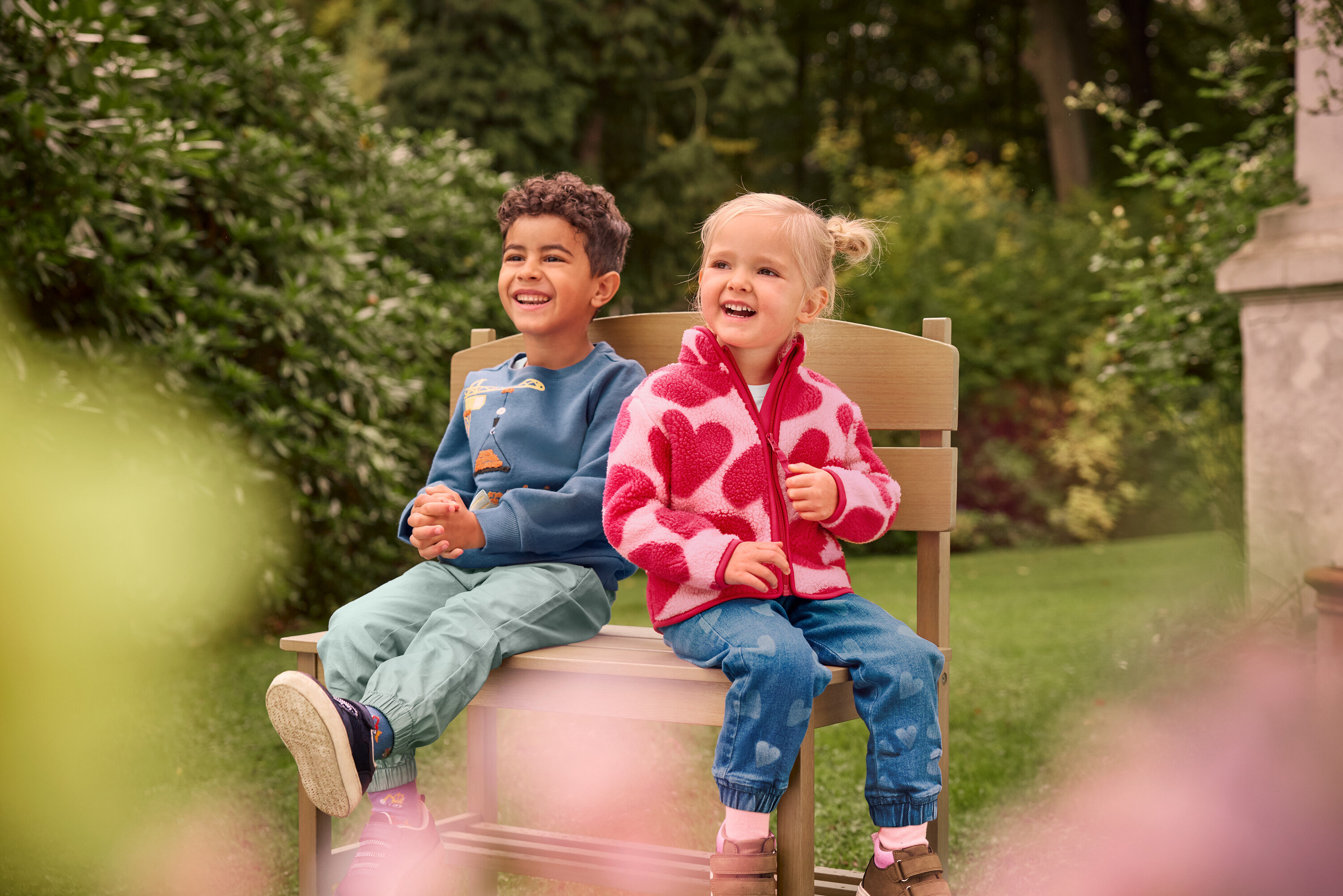 Chlapec a dievča sedia a smejú sa na malej záhradnej lavičke s odkladacím priestorom.