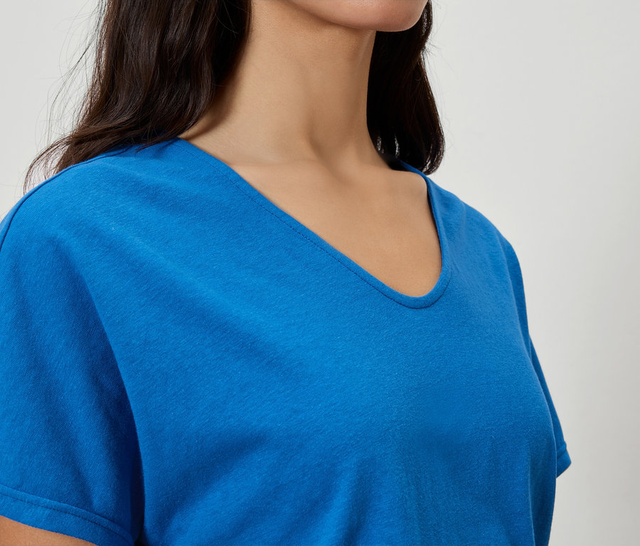 Detailný záber ženy v modrom tričku s véčkovým výstrihom.