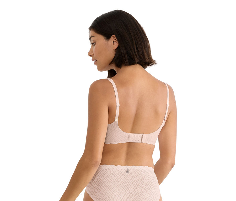 Žena zozadu, má na sebe svetloružovú podprsenku a zodpovedajúce nohavičky so vzorom.