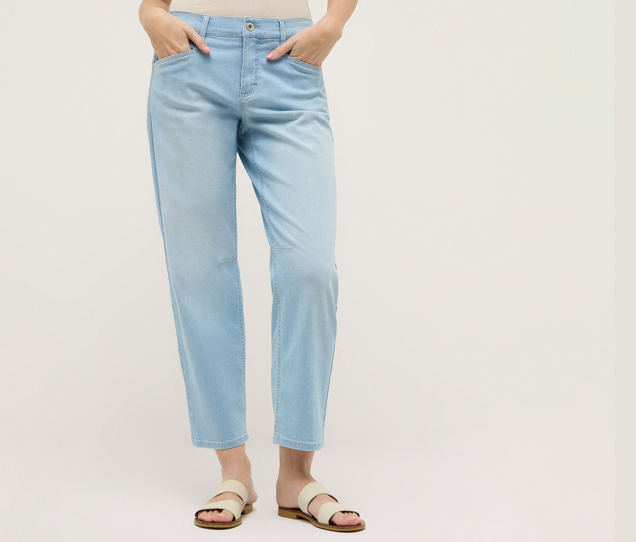 Žena v svetlomodrých nohaviciach Angels Denim »Evy Cool« O-Shape a sandáloch. Ruky má vo vreckách.