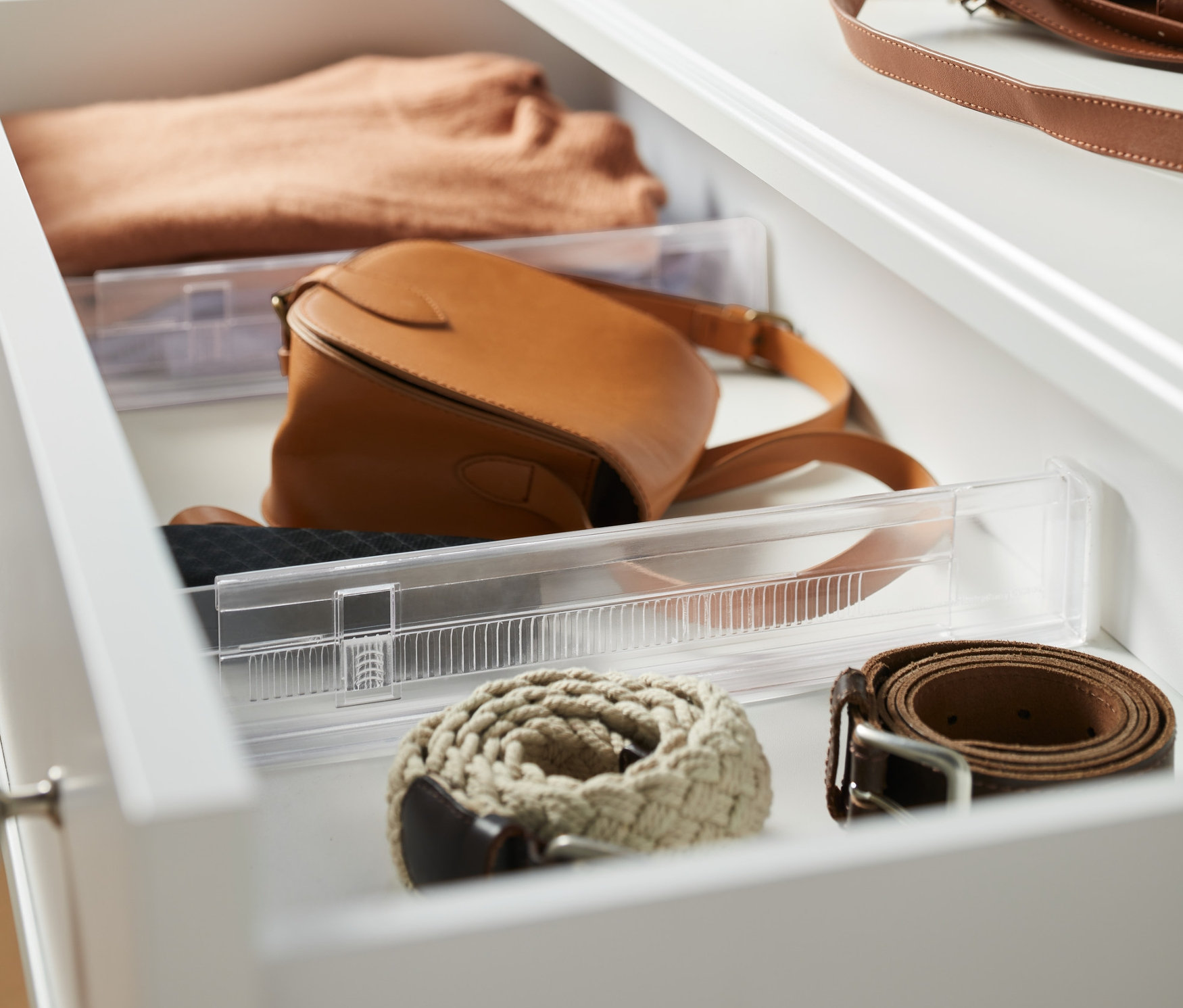 Otvorená zásuvka s dvoma rozdeľovačmi do zásuviek, svetrom, kabelkou a opaskami.