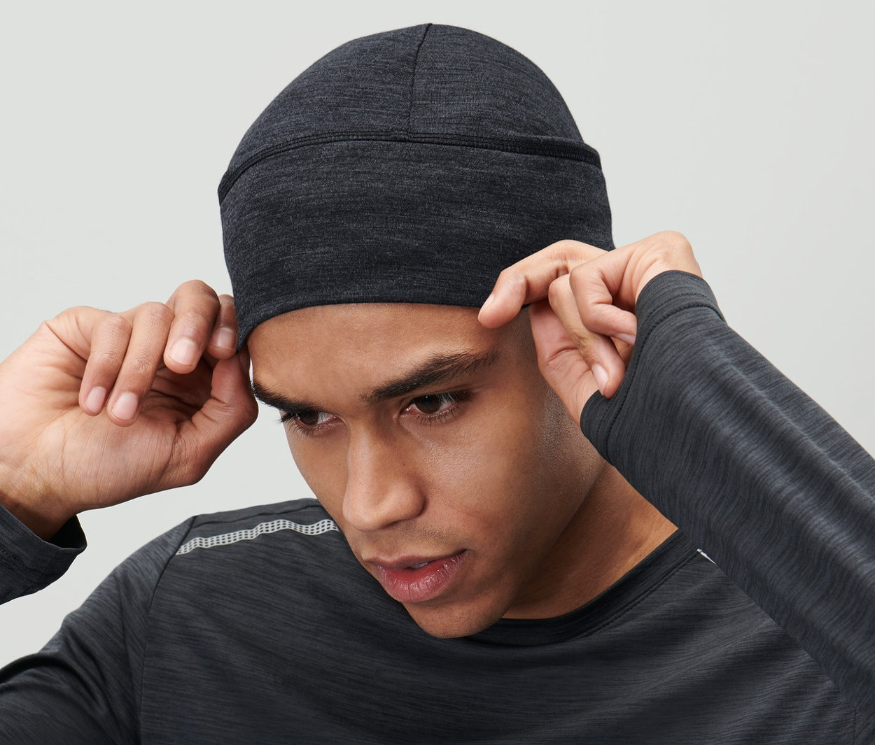 Muž si upravuje na hlave antracitovú čiapku s merino vlnou.
