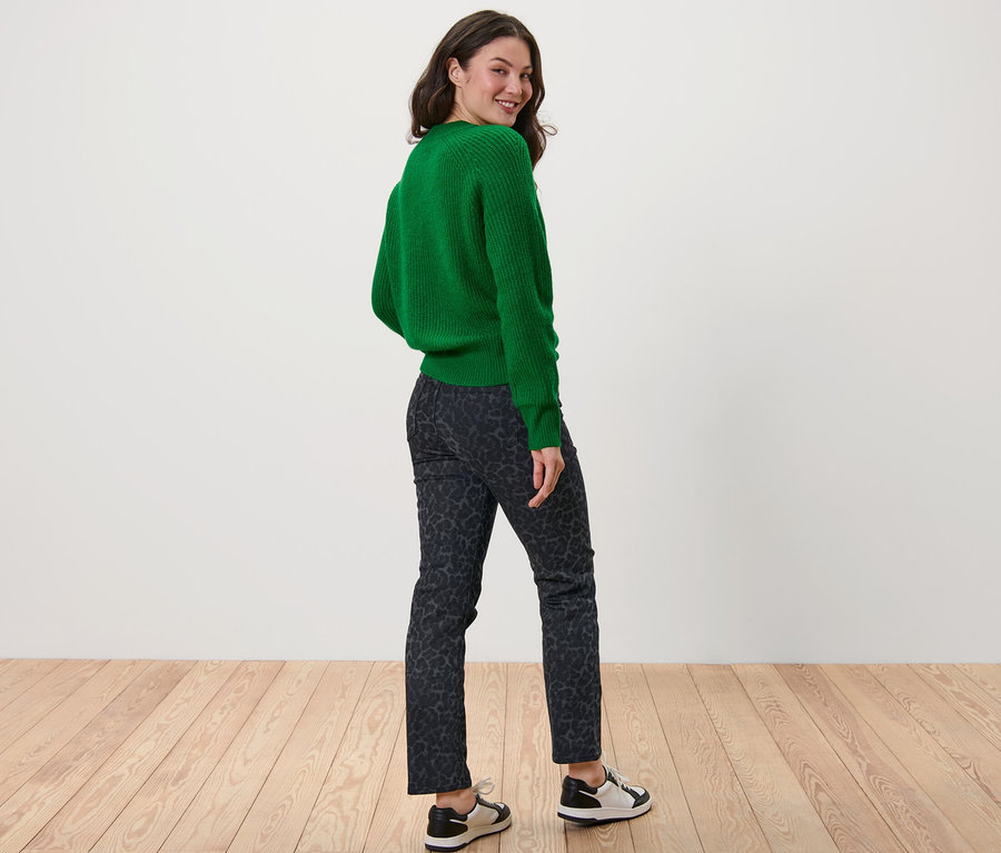 Žena sa pozerá cez plece a má na sebe zelený sveter a Straight Jeans s potlačou – strih »Kira«.