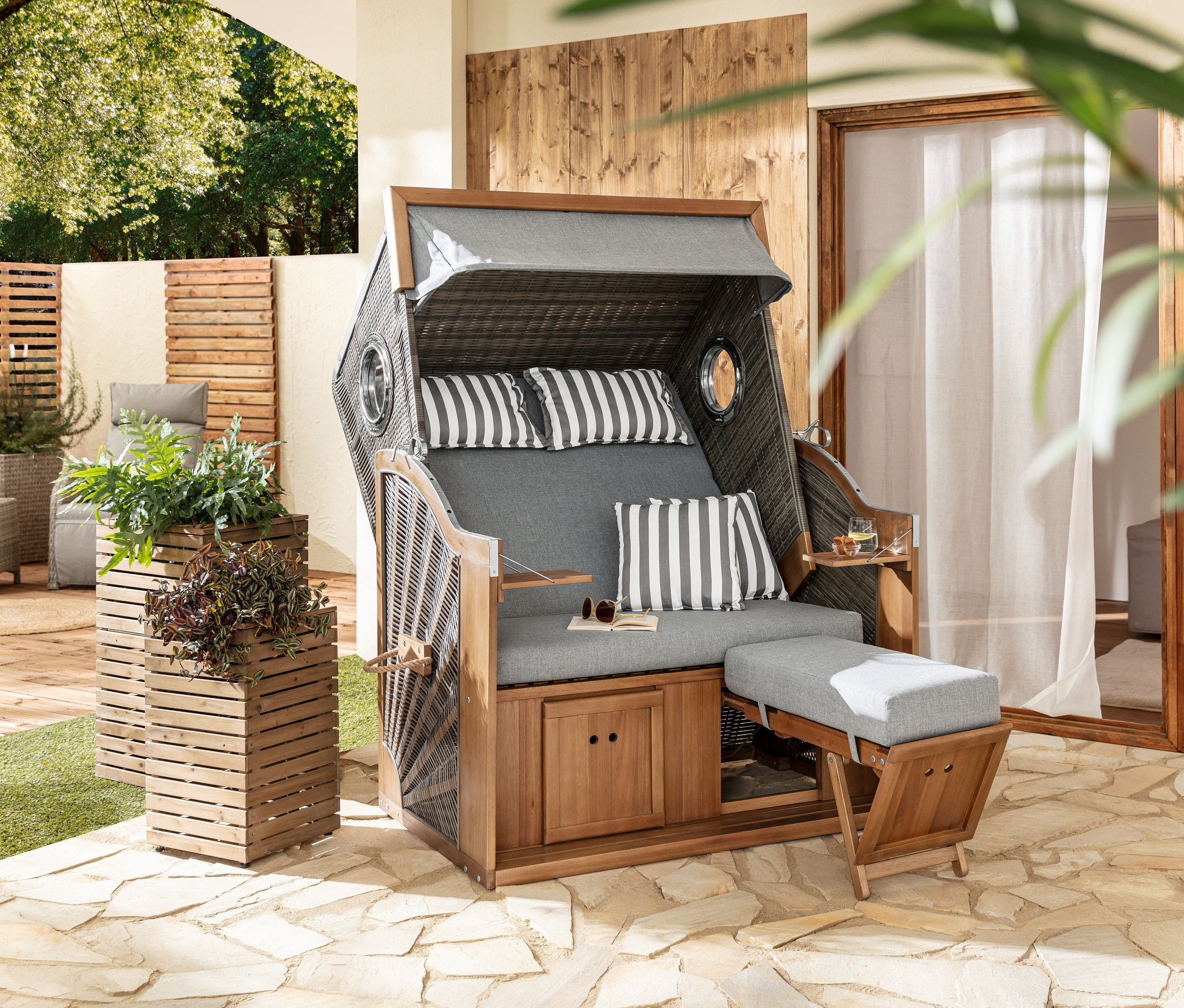 Dva stĺpovité kvetináče »Tinus« stoja vedľa plážového koša XL prémiovej kvality s 2 výklopnými stolíkmi.