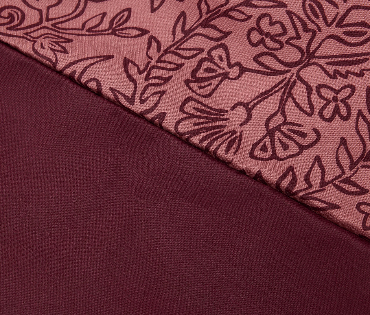 Detail bordovej látky s kvetinovým vzorom.