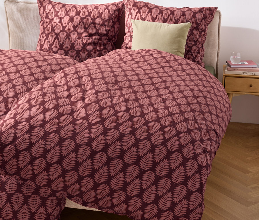 Detailný záber postele s posteľnou bielizňou zo zimného džerseja štandardnej a nadmernej veľkosti s listovým vzorom.