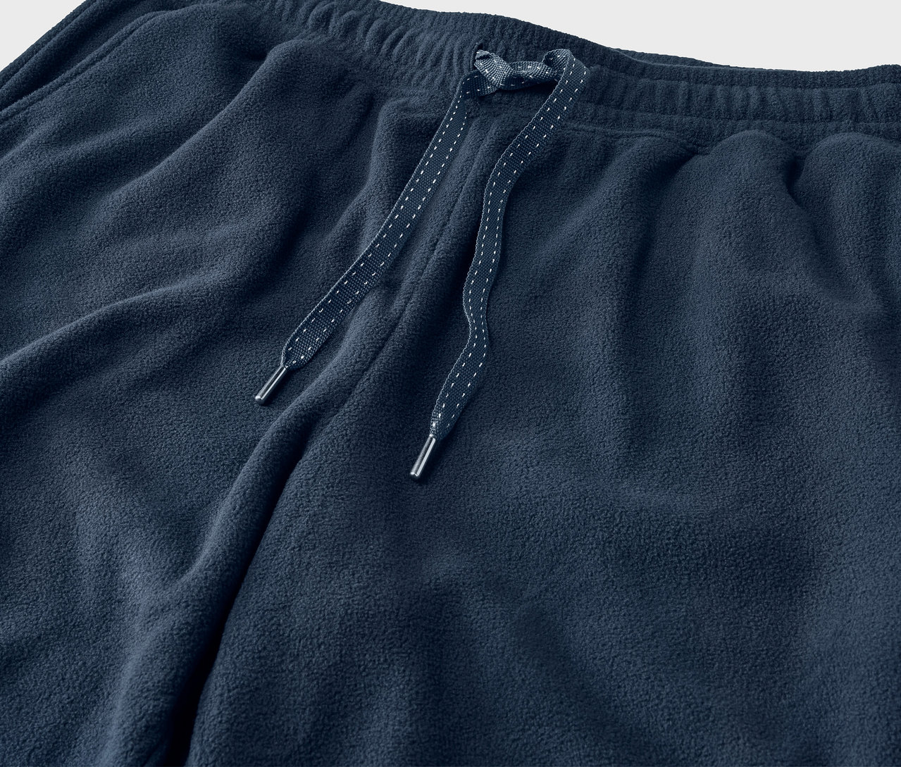 Detail modrých teplákov so šnúrkami v páse.