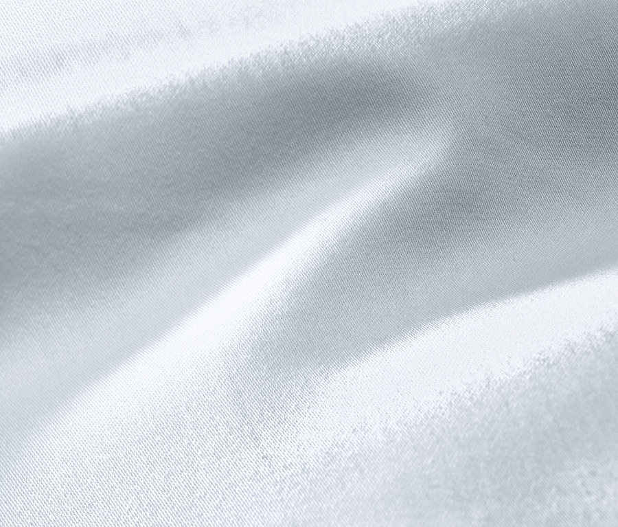 Detailný záber bielej posteľnej bielizne z bavlny a saténu v nadmernej veľkosti.