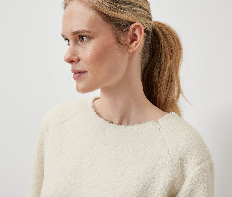 Detail profilu blondínky s vlasmi stiahnutými do chvosta, ktorá má na sebe krémový sveter.