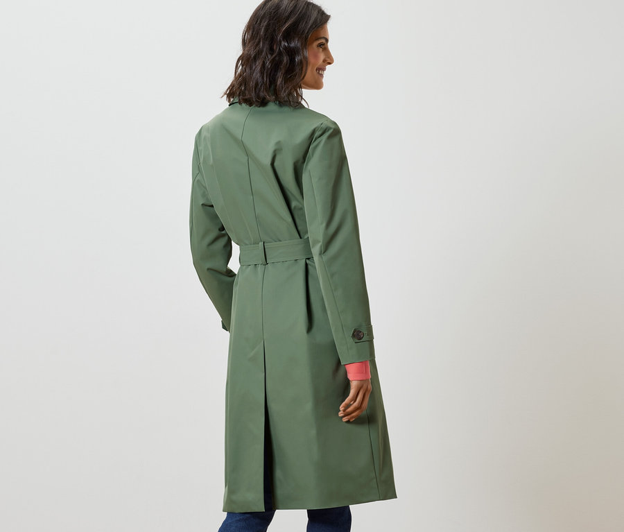 Žena sa pozerá cez rameno a má na sebe svetlozelený trenčkot.