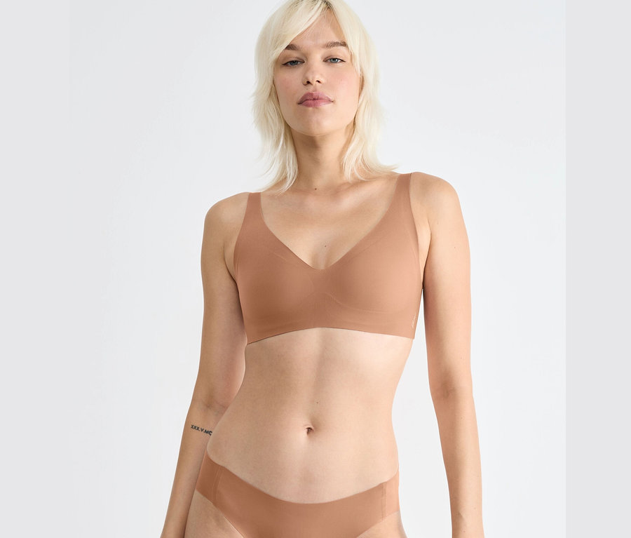 Blondínka má na sebe hnedú podprsenku sloggi ZERO Feel 2.0 Soft Bra.