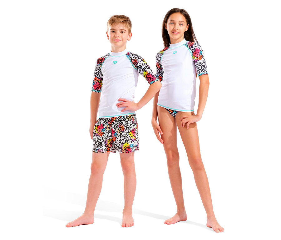 Dve deti, chlapec a dievča, stoja vedľa seba na bielom pozadí. Obaja majú na sebe biele topy s farebnými rukávmi a farebné spodky.