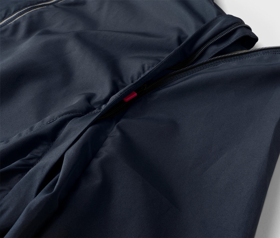 Detailný záber na tmavomodrú bundu s čiastočne otvoreným zipsom.