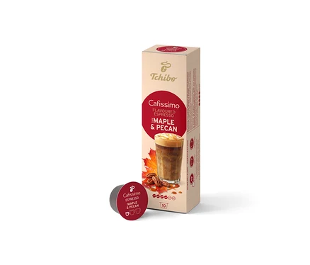 Béžová škatuľka Cafissimo Flavoured Espresso Maple & Pecan (10 kapsúl) stojí vzpriamene, pred ňou leží jedna tmavočervená kapsula. Škatuľka zobrazuje kávový nápoj, javorové listy a pekanové orechy.