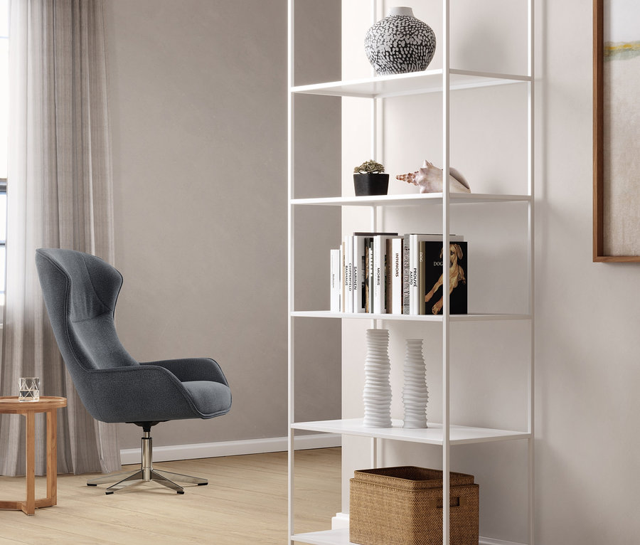 Modré otočné kreslo stojí vedľa bieleho kovového regálu.