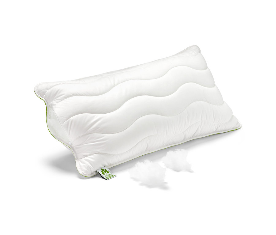 Biely vankúš irisette® greenline Megafil® BIO, cca 65 x 100 cm, leží na bielom pozadí vedľa dvoch chumáčov výplne.