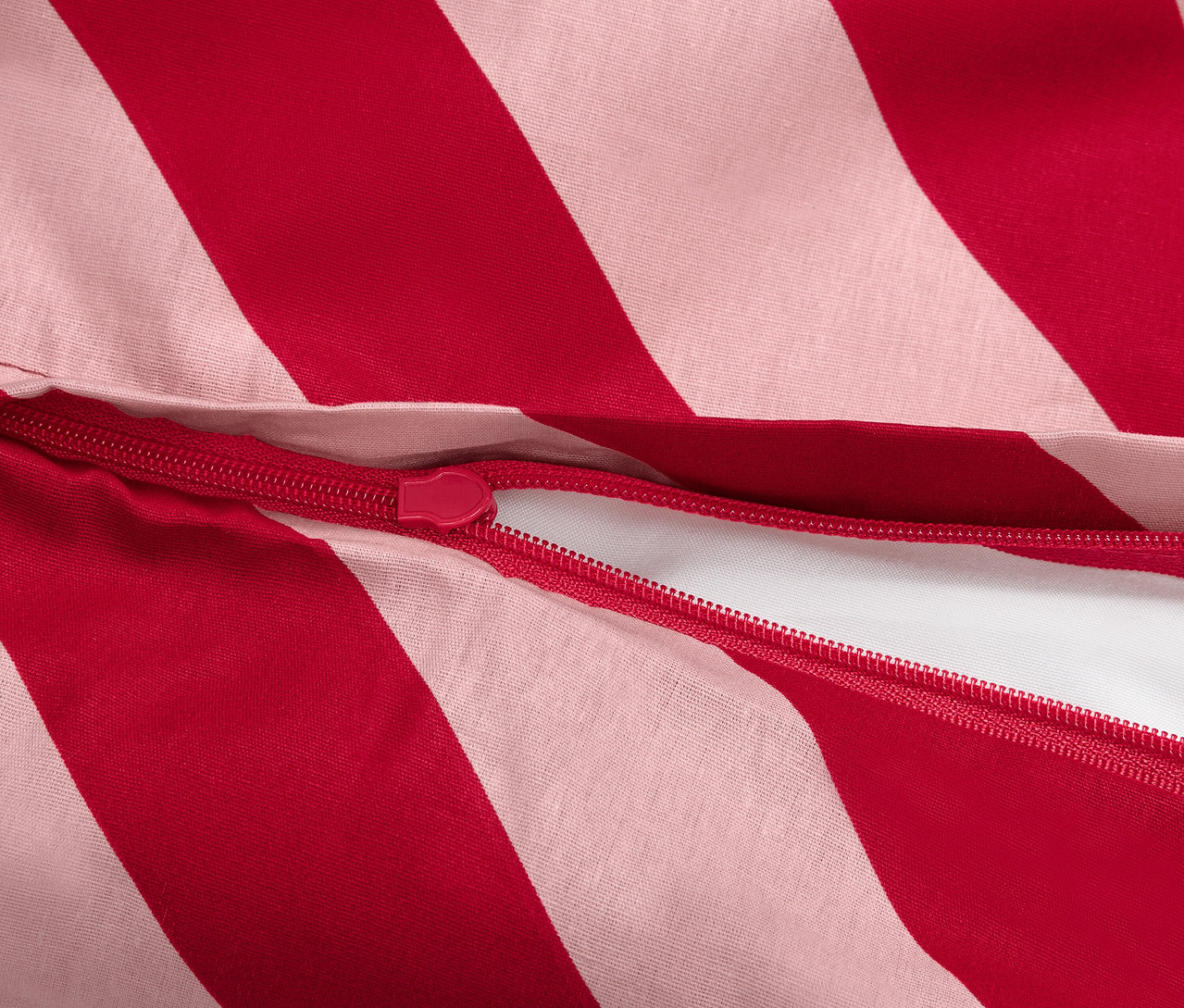 Detail červeno-bielej pruhovanej obliečky na perinu so zipsom.