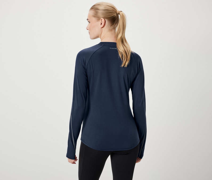 Zozadu je vidieť žena s blond vlasmi stiahnutými do copu, oblečená v tmavomodrom tričku s dlhým rukávom a čiernych legínach.