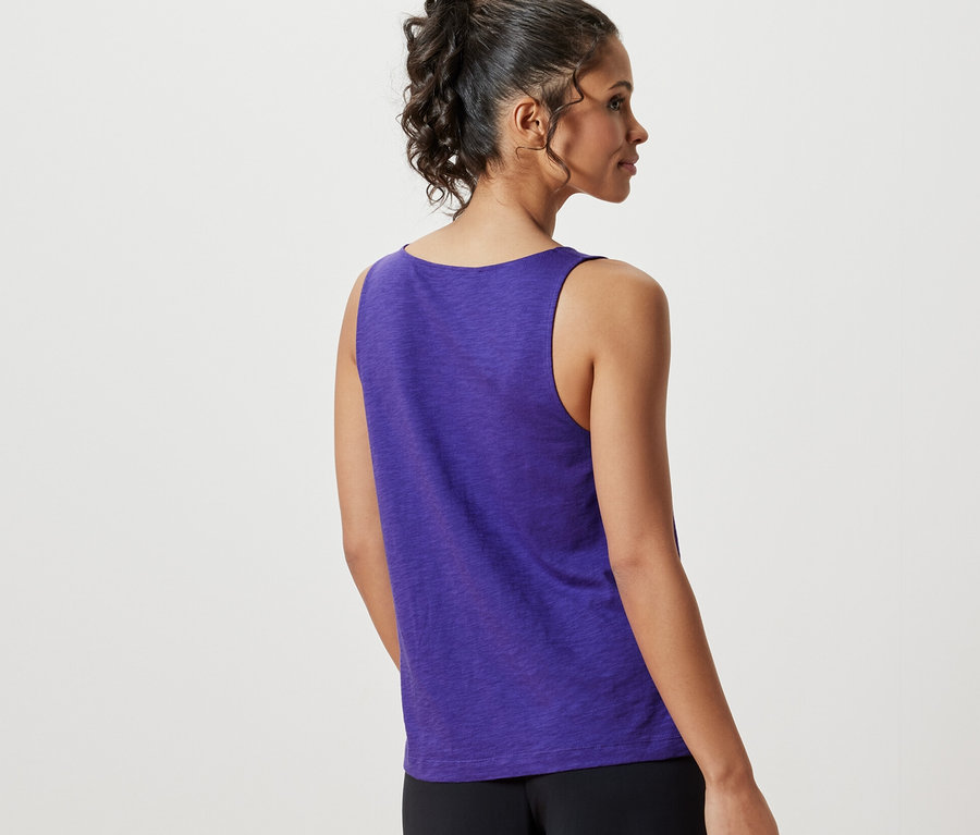 Žena z pohľadu zozadu má na sebe fialový top z modalovej zmesi a čierne nohavice.