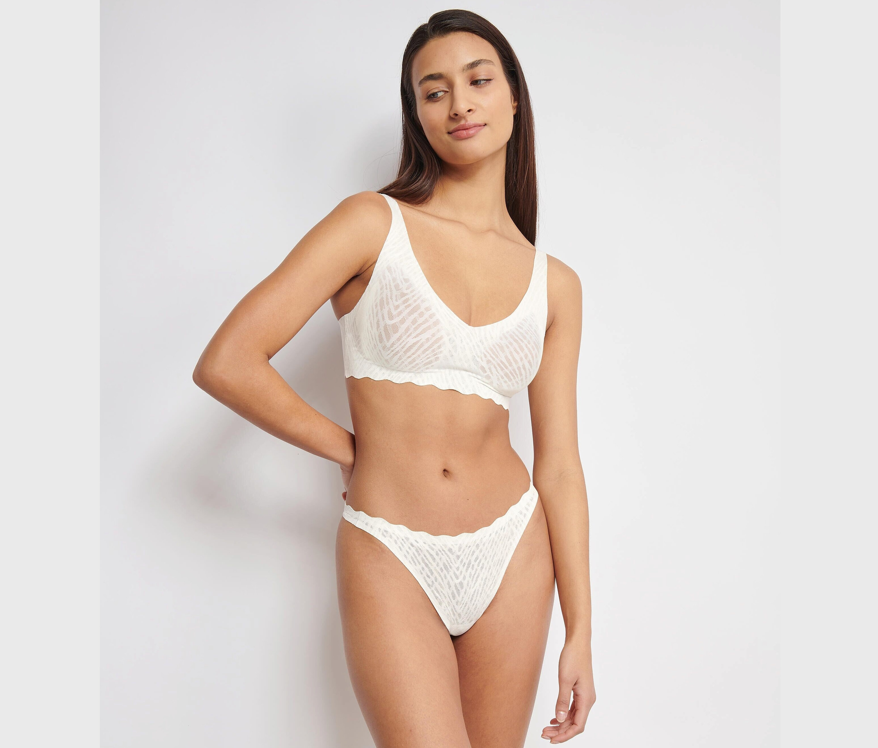 Žena pózuje v bielej súprave spodnej bielizne sloggi ZERO Feel Bliss Soft Bra.