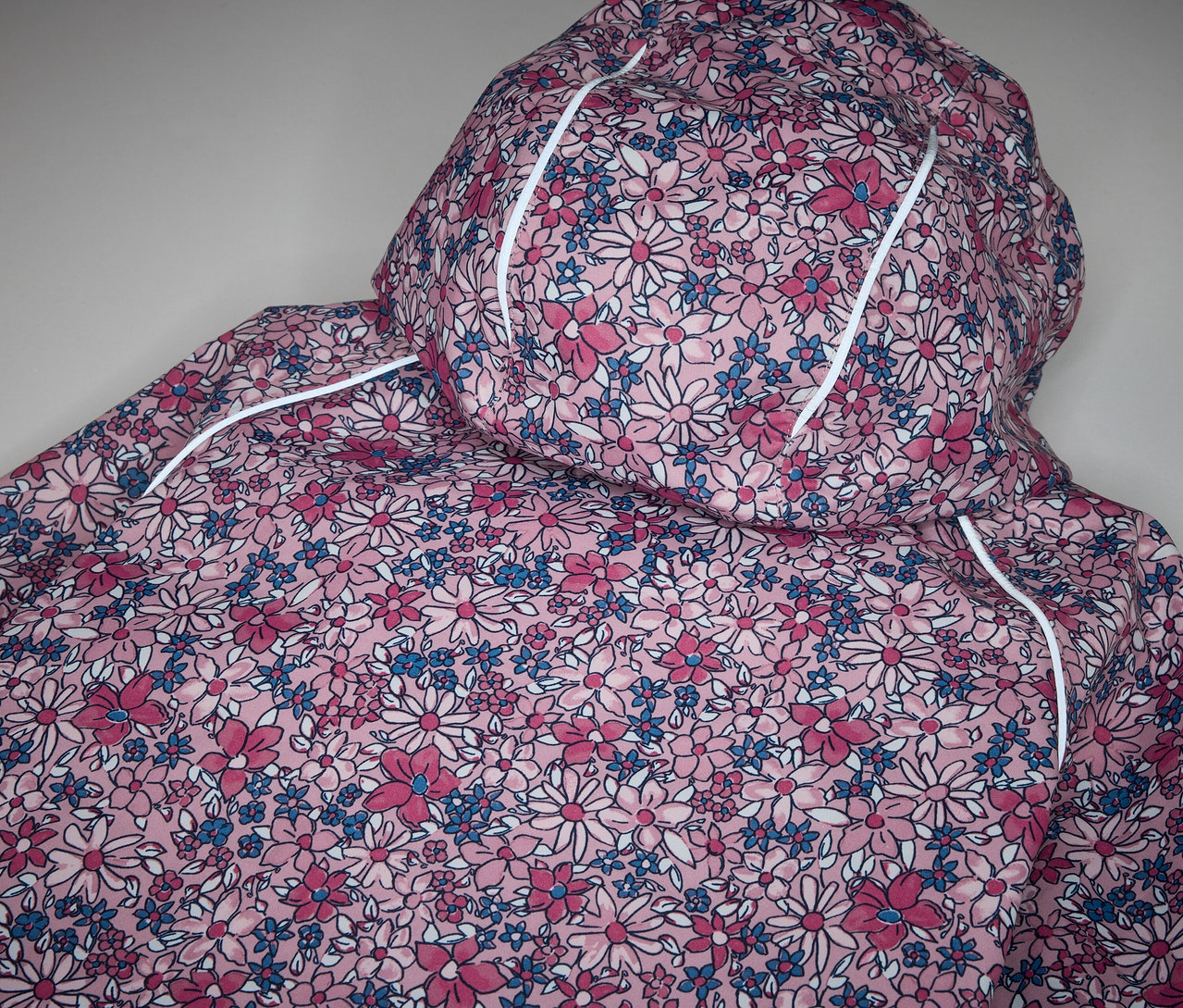 Detail detskej termo bundy do dažďa s kvetinovou potlačou.