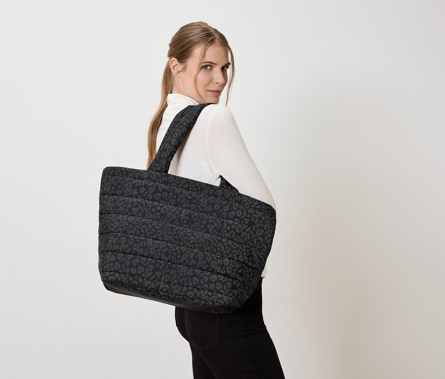 Žena s veľkou prešívanou taškou s leopardím vzorom cez rameno.