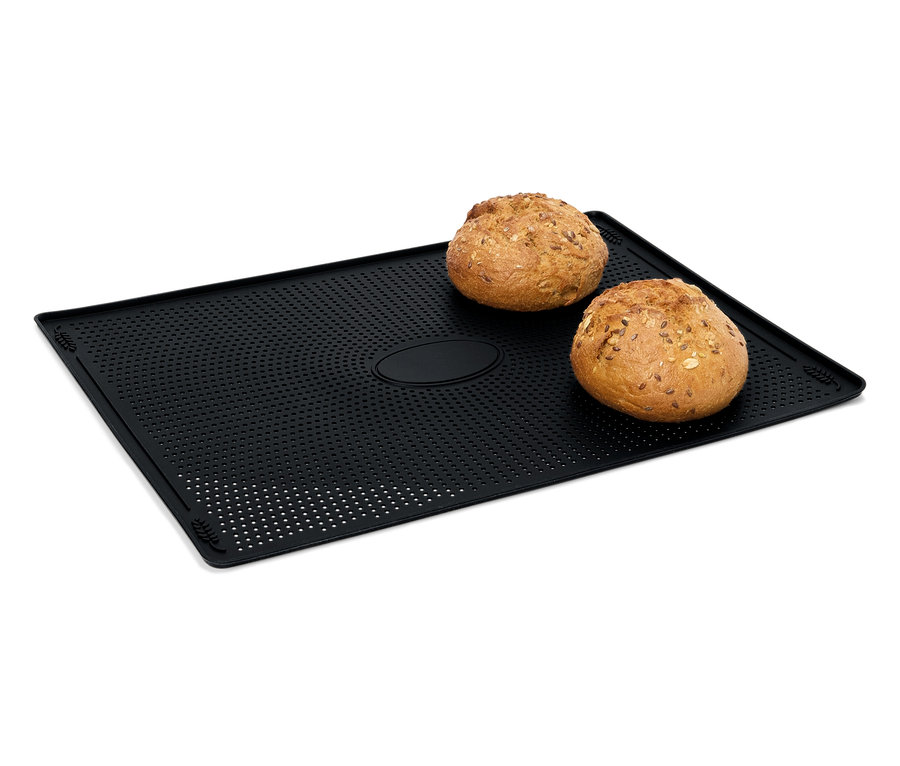 Dva bochníky chleba ležia na čiernej perforovanej podložke na pečenie.