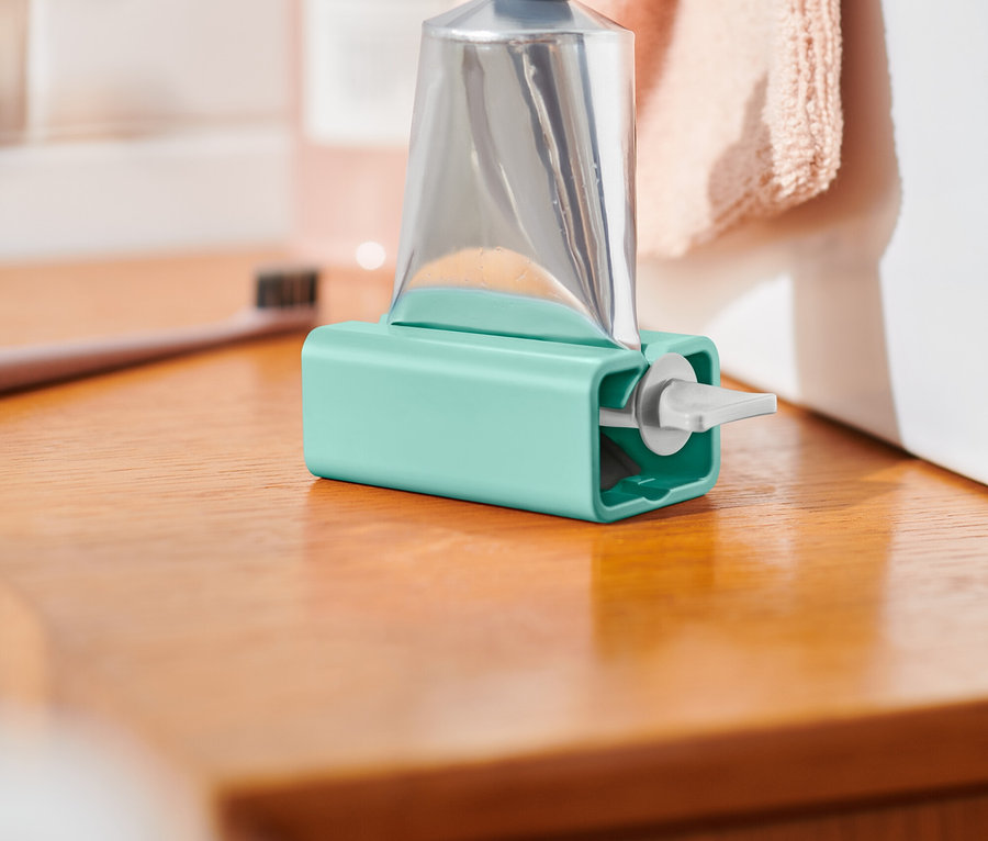 Strieborná tuba v modrom držiaku stojí na drevenej doske.