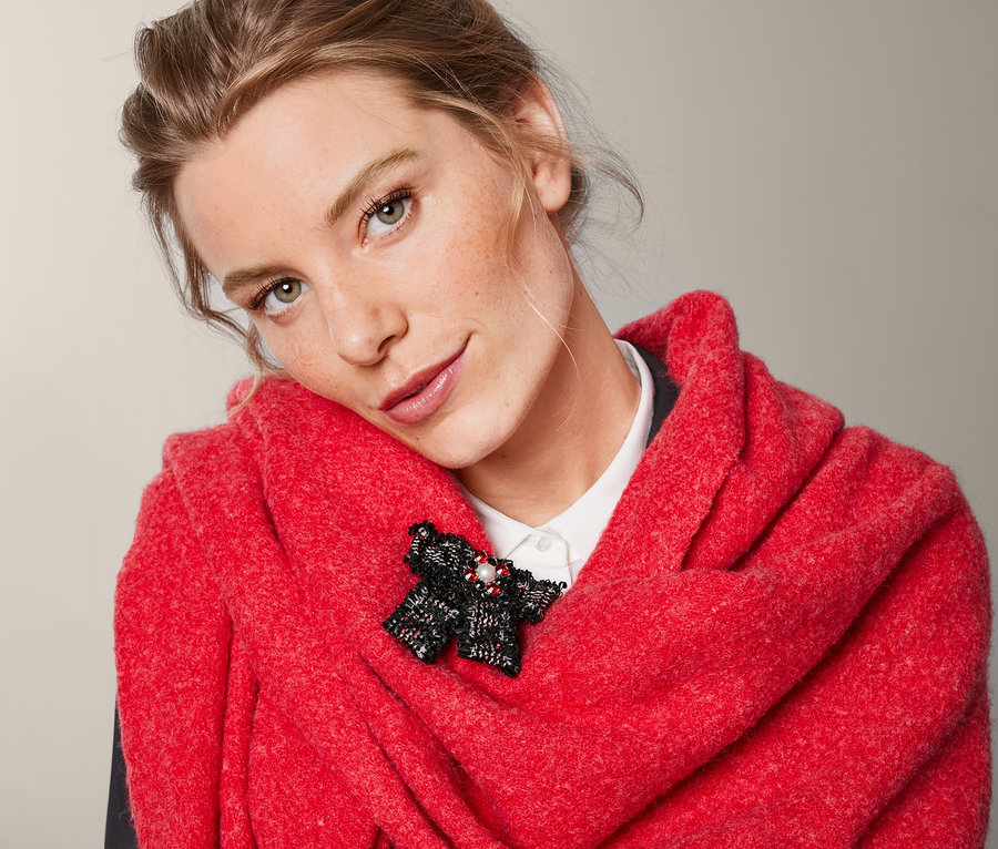 Žena s červenou šatkou a brošňou v tvare mašle z tvídu.