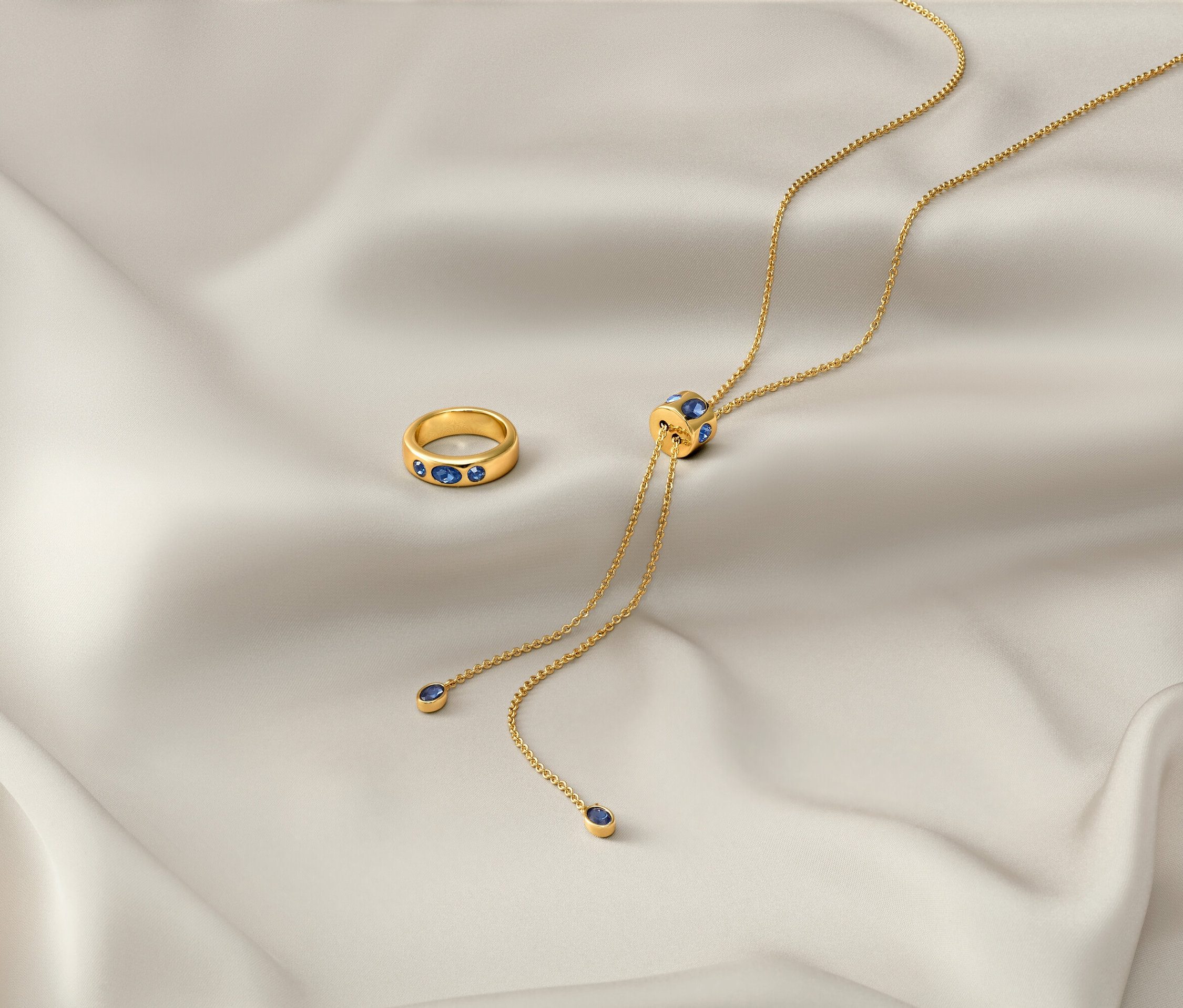 Na bielej látke leží zlatá retiazka »Iconic« a zlatý prsteň »Iconic«.