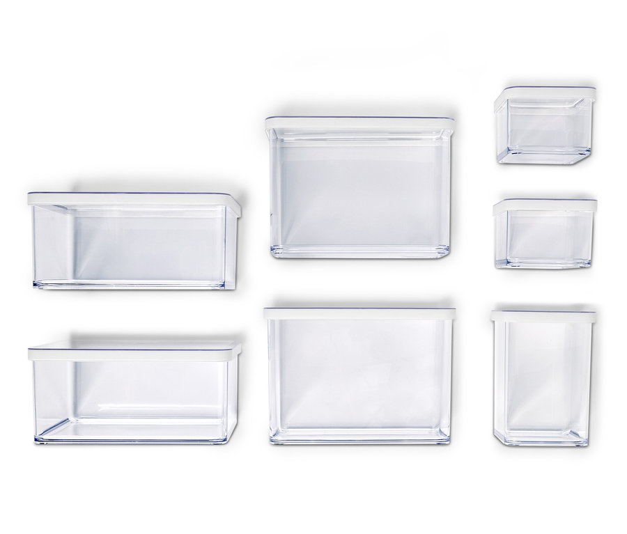 Sedem prázdnych, priehľadných úložných nádob s bielymi viečkami rôznych veľkostí usporiadaných na bielom pozadí.
