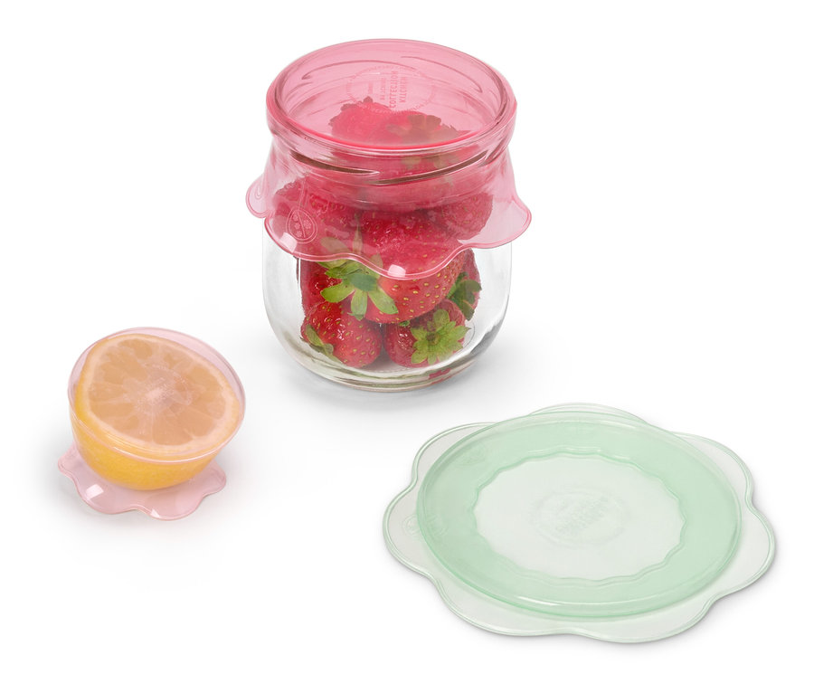 Pohár s jahodami pod ružovým viečkom stojí vedľa polovice citróna pod ružovým viečkom a zeleného viečka.