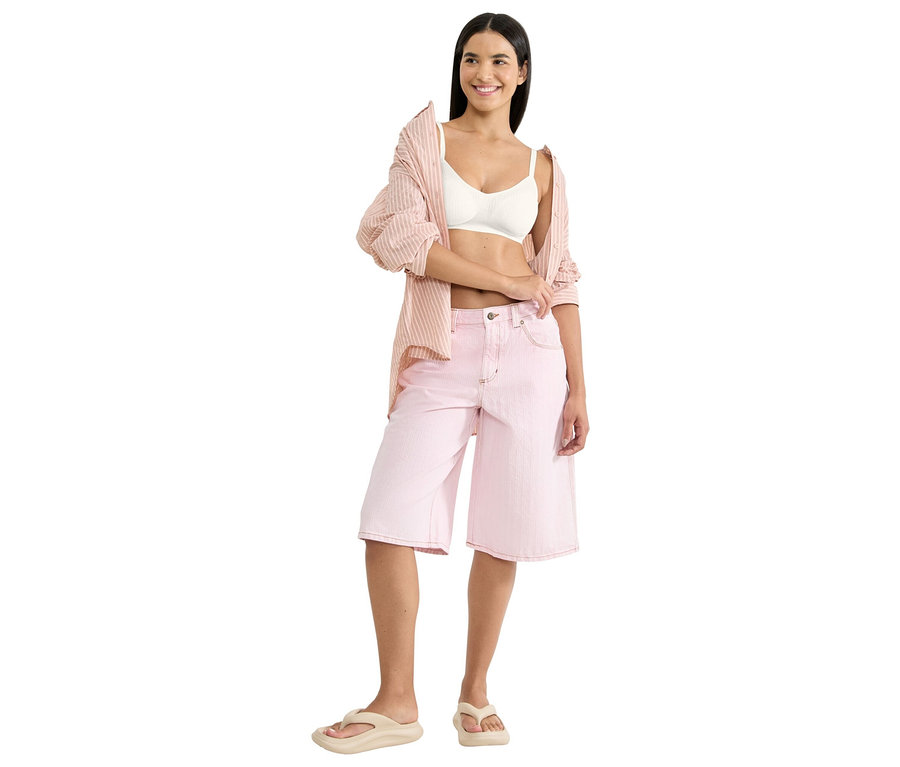 Žena má na sebe bielu braletku, ružovú košeľovú blúzku s prúžkami a ružové culottes šortky s béžovými žabkami.