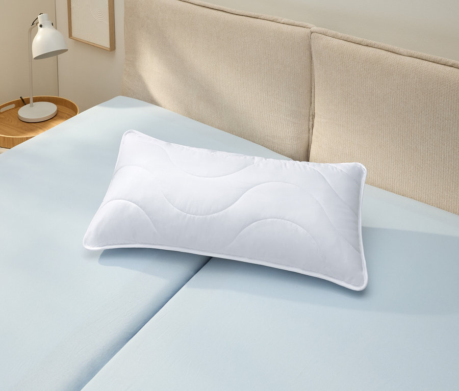 Biely vankúš s možnosťou vyvárania (cca 80 x 40) leží na svetlomodrej plachte.