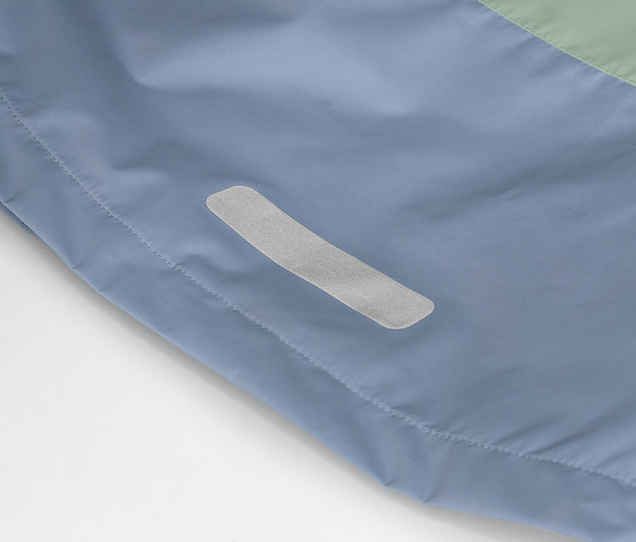 Detailný záber modro-zelenej bundy s reflexným pásikom na boku.