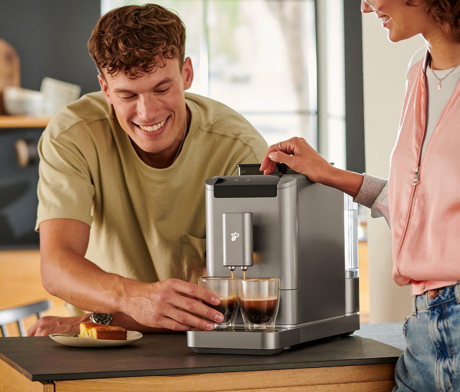 Muž sleduje, ako sa káva leje do dvoch pohárov z plnoautomatického kávovaru »Esperto2 Caffè« v Titanium Silver farbe.