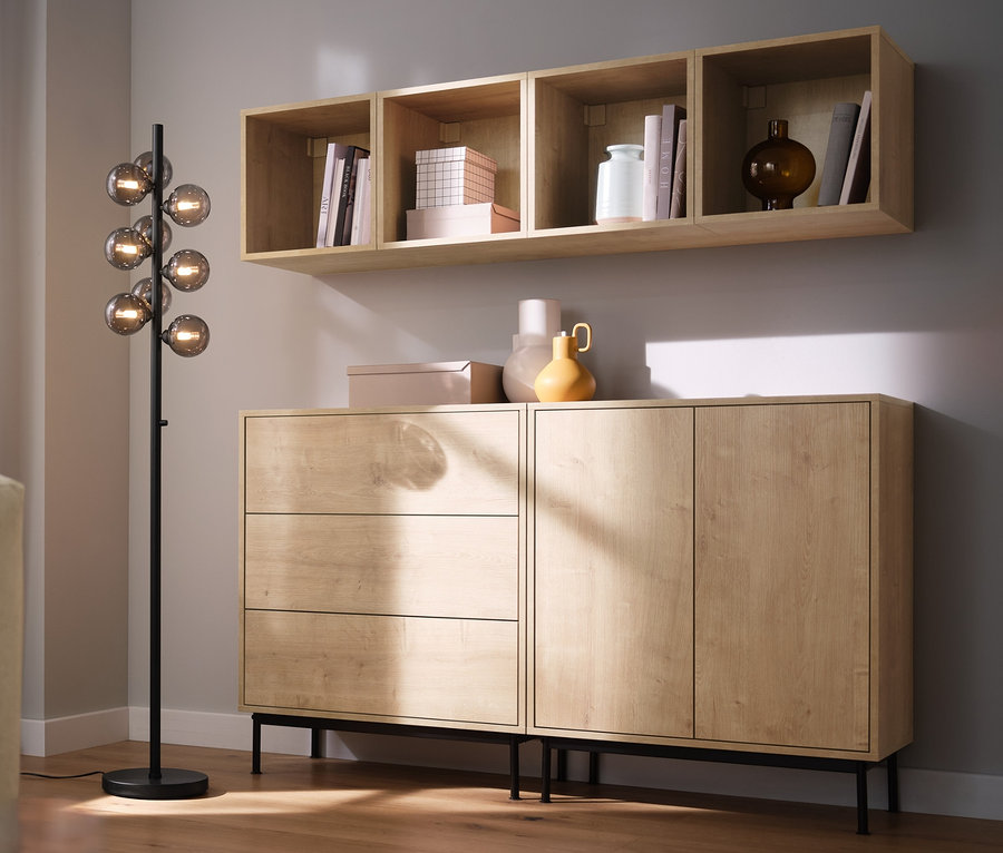 Obývacia izba s pohovkou, stojacou lampou »Sklenené gule« a regálovými modulmi »Flemming« v dubovom dekore.