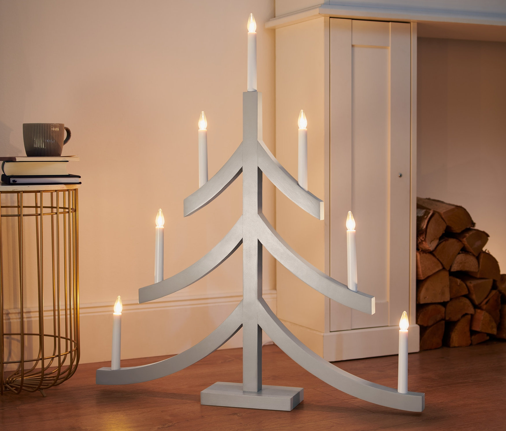 Sivý XL svietnik s LED v tvare vianočného stromčeka stojí na podlahe.