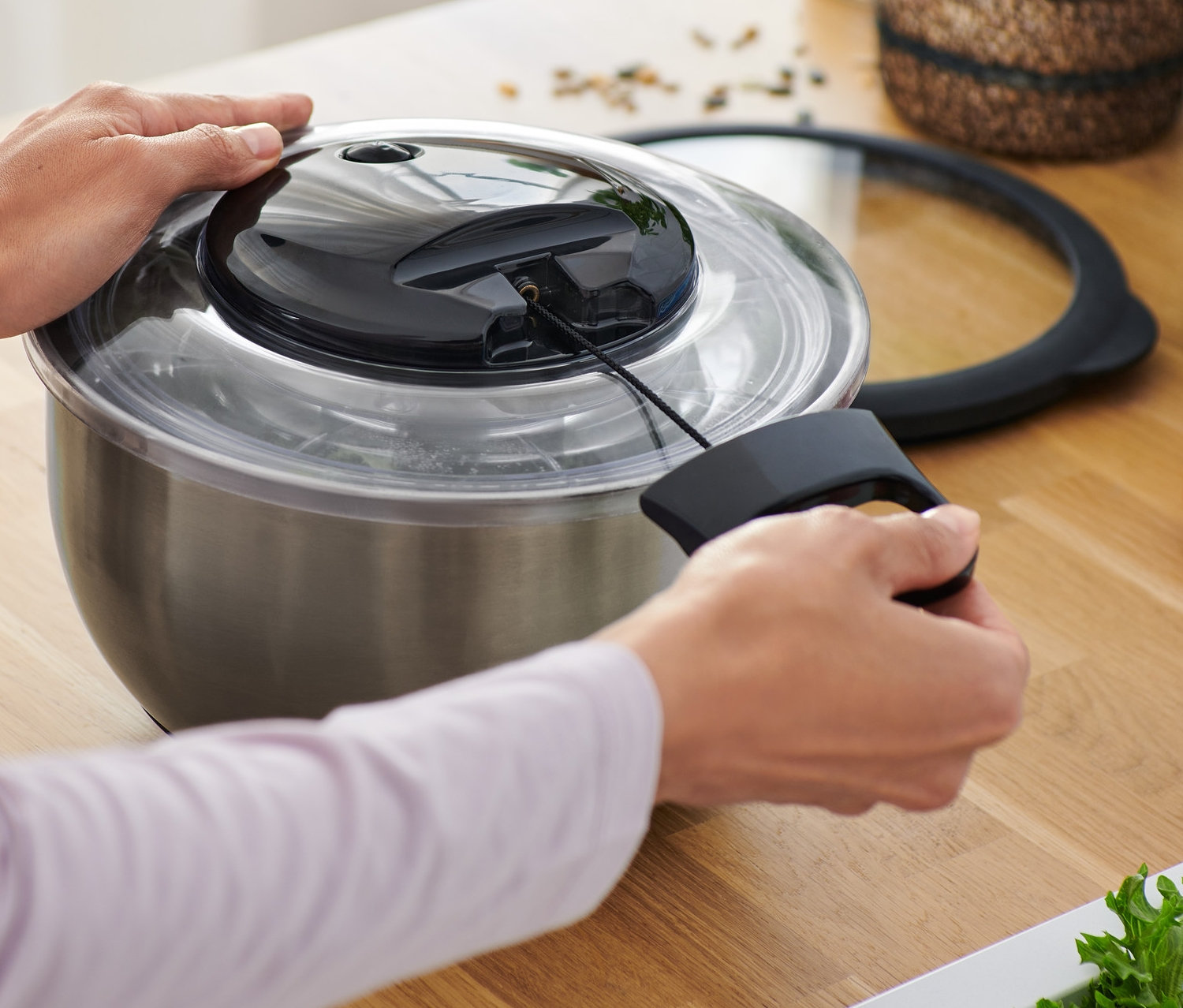 Osoba používa odstredivku na šalát z ušľachtilej ocele s vekom v kuchyni.