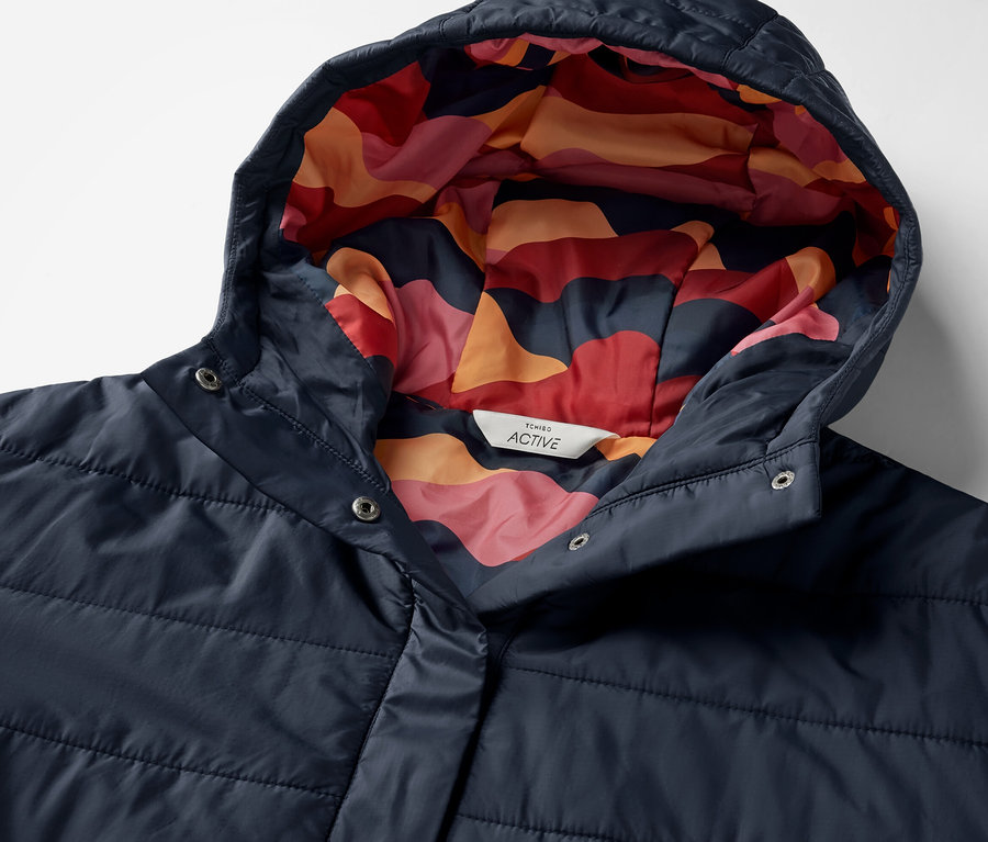 Detail modrého outdoorového ponča s kapucňou s farebným vzorom vnútri.
