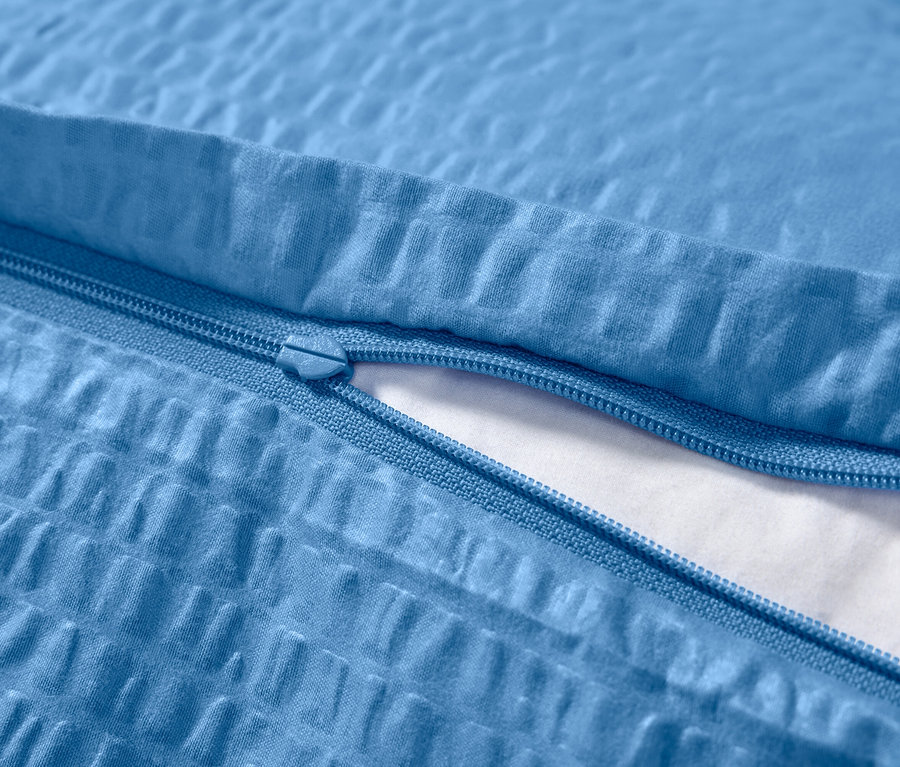 Detail modrej krepovej posteľnej bielizne so zipsom.